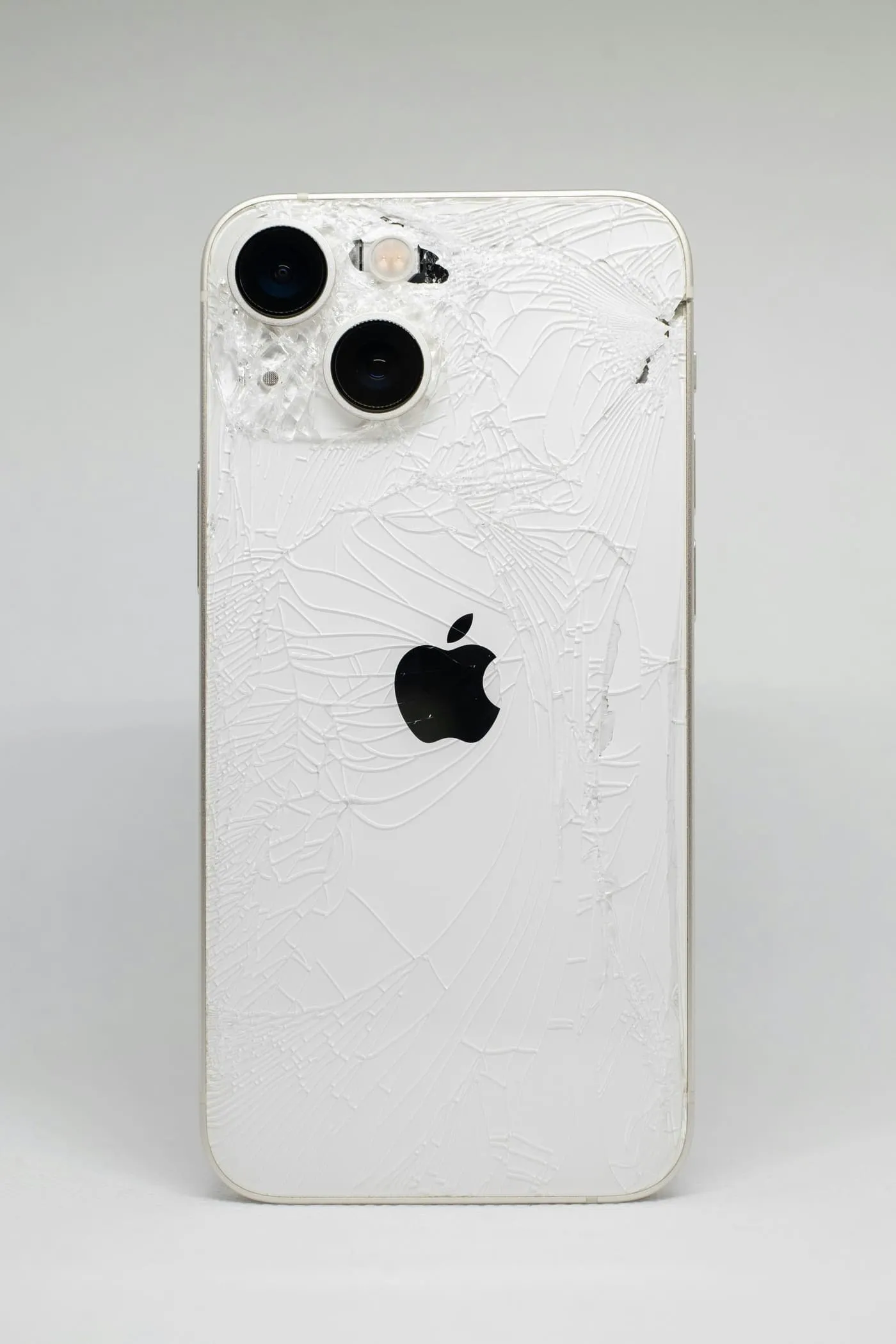 Technician replacing the cracked back glass on a phone at the repair bench